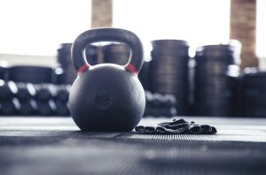 Closeup image of a kettle ball and sports gloves in gym